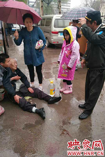 女孩為倒地老人撐傘。