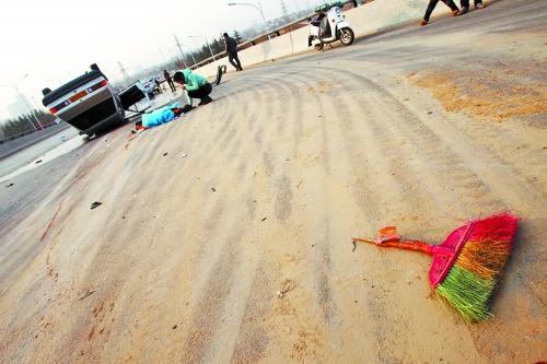 被撞的環(huán)衛(wèi)工躺在地上，身上蓋著藍(lán)色布塊，現(xiàn)場除散落的汽車碎片外，還留有被撞斷的掃帚。