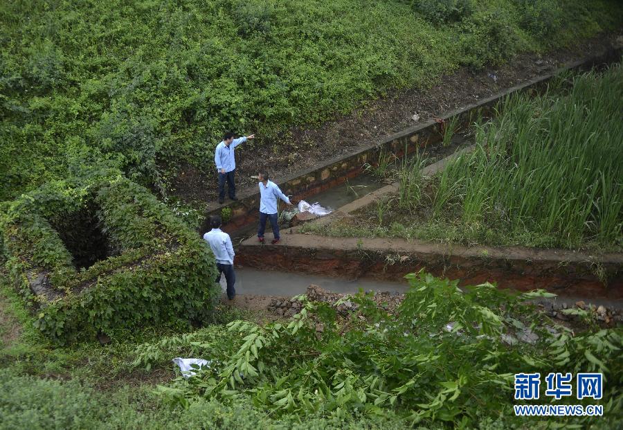 5月18日，工作人員在槽罐車泄漏現(xiàn)場附近的水渠邊查看情況。