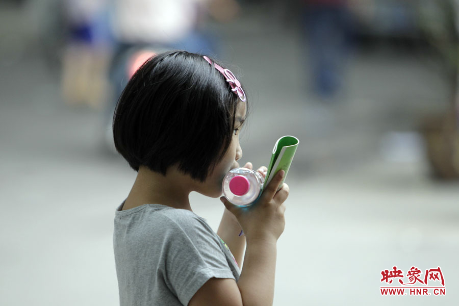 6月7日，鄭州回中考點，一名孩子拿著一瓶礦泉水，等待哥哥走出考場