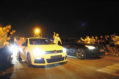 8月24日晚，東壩中街飆車現(xiàn)場，兩輛車并排等待出發(fā)指令，旁邊許多愛好者前來觀看比賽。新京報記者