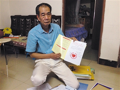 翻出一家網(wǎng)站贈予的“中國好人”證書，區(qū)少坤單膝跪在地上，“你看，我是中國好人啊。” 范春旭 攝