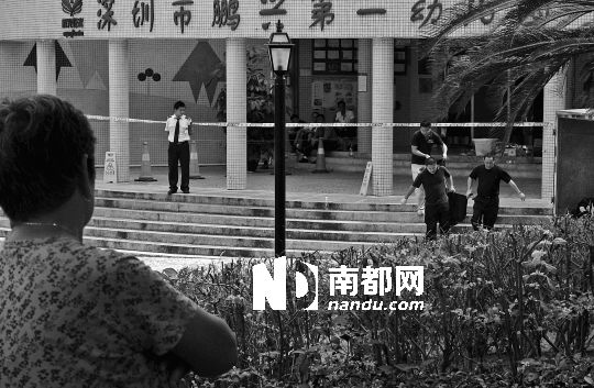 →7月19日，鵬興花園第一幼兒園門前，民警在現(xiàn)場進(jìn)行完勘查取證后，園長和保安的尸體被運走。南都記者 徐文閣 攝