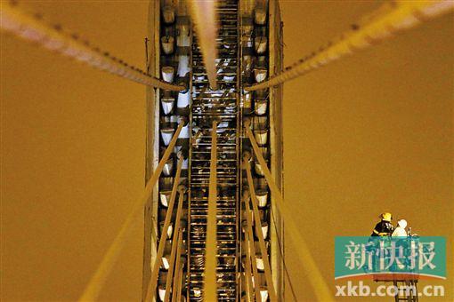 截至今日零時(shí)，男子仍未有下橋舉動(dòng)。圖為公安和消防人員乘消防云梯在高空上和男子交談。