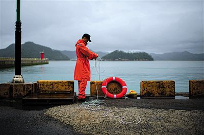 7月6日，韓國(guó)珍島，一名海岸警察在港口系救生圈。4月，客輪在珍島近海發(fā)生沉船事故后，仍有11人下落不明。