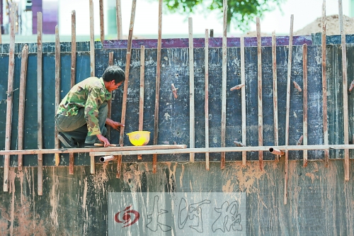 　　烈日下，狹窄的架子上，工人正用錘子固定樁基。