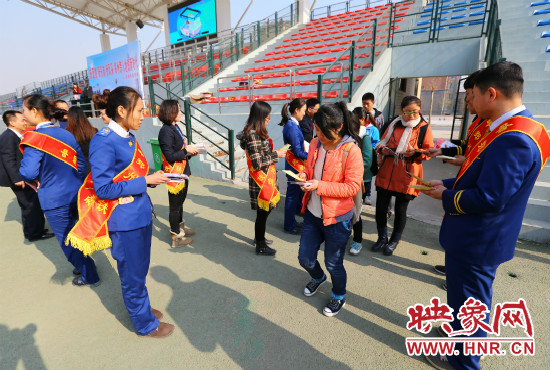 活動現(xiàn)場工作人員給同學(xué)們發(fā)放宣傳冊、環(huán)保袋。