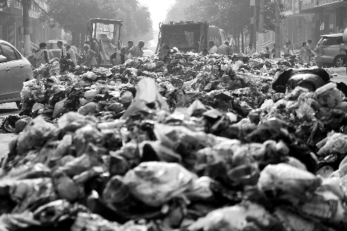 垃圾堆滿整個(gè)路口，環(huán)衛(wèi)工人們正在清理