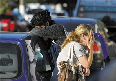 27日，遇難者親友在火災(zāi)現(xiàn)場旁哭泣。