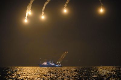 22日，搜救人員在照明彈的光亮下連夜搜救。