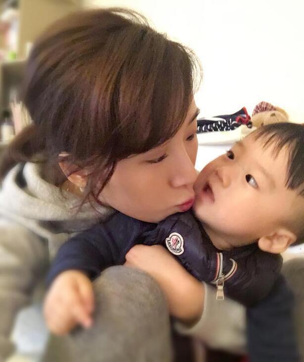 照片中李念狂吻兒子，小寶貝自顧自地玩著。