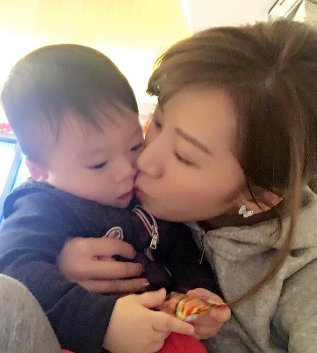 照片中李念狂吻兒子，小寶貝自顧自地玩著。