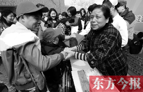 昨日，鄭大四附院的大樓前，“面人鄭”鄭玉芬（右）向前來捐款的殘疾人表示感謝