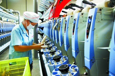 7月3日，在鄧州市永泰棉紡有限公司電腦控制全自動紡紗車間，紡織工人正在生產棉紗。