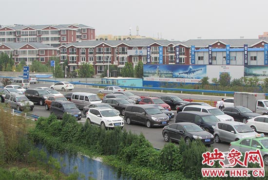 記者看到鄭州機(jī)場(chǎng)收費(fèi)站口車(chē)輛排隊(duì)，與此形成鮮明對(duì)比的是，路的對(duì)面（另一半幅）卻車(chē)輛較少，通行順暢。