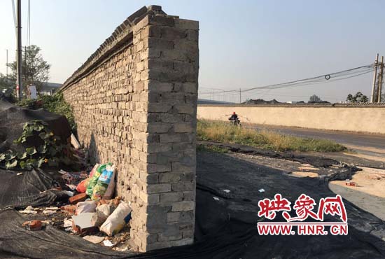 一墻之隔，一邊是道路，一邊是垃圾和荒草，市民質(zhì)疑其為遮羞墻。