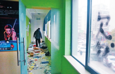 　健身會(huì)所地上一片狼藉，玻璃上噴著黑色“欠錢”二字。
