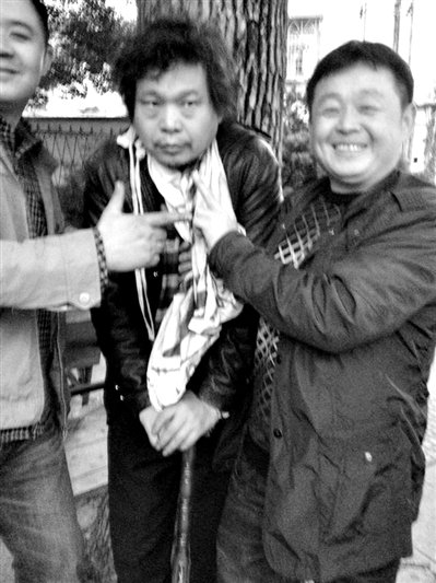 兩名接訪人員與患有癌癥的訪民段新德合影時(shí)，面帶笑容擺出勝利的手勢(shì)。