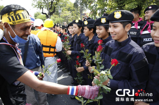 2013年12月03日,曼谷總理府與曼谷警署允許反政府示威民眾進(jìn)入,雙方進(jìn)入暫時(shí)“停戰(zhàn)”狀態(tài)迎接泰王生日。曼谷警察總署,女警們手持鮮花送給反政府示威民眾。圖片來源:Manish Swarup/東方IC
