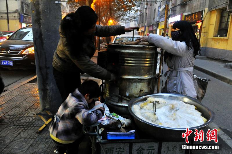 男孩西安路燈下寫(xiě)作業(yè) 媽媽邊賣(mài)紅薯邊輔導(dǎo)
