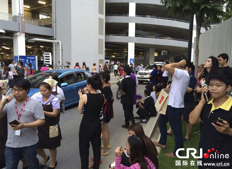 當(dāng)?shù)貢r間2014年5月5日，泰國清萊，工人們站在一棟大樓外避難。