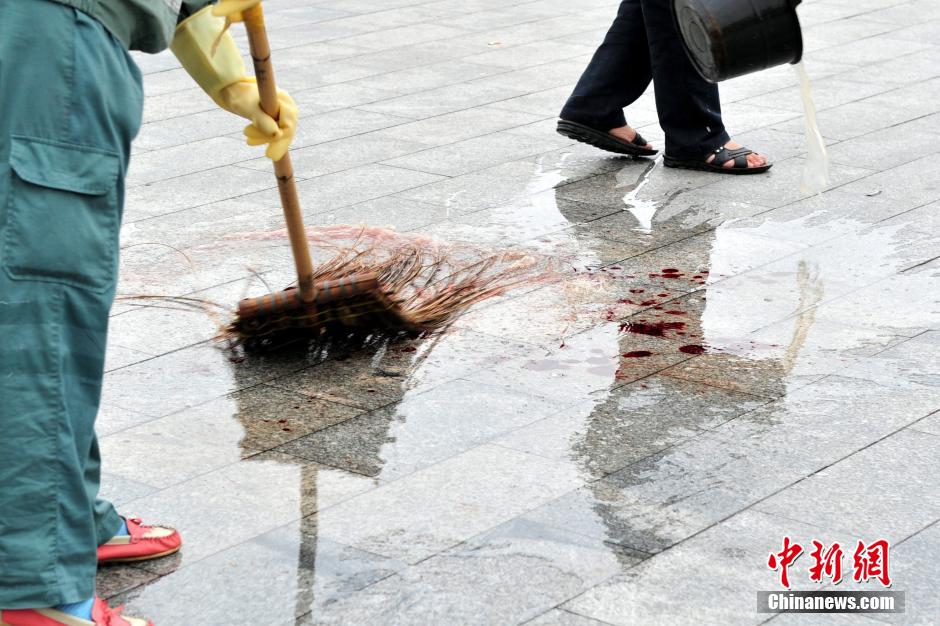 圖為環(huán)衛(wèi)工人在清理案發(fā)地點(diǎn)的血跡。