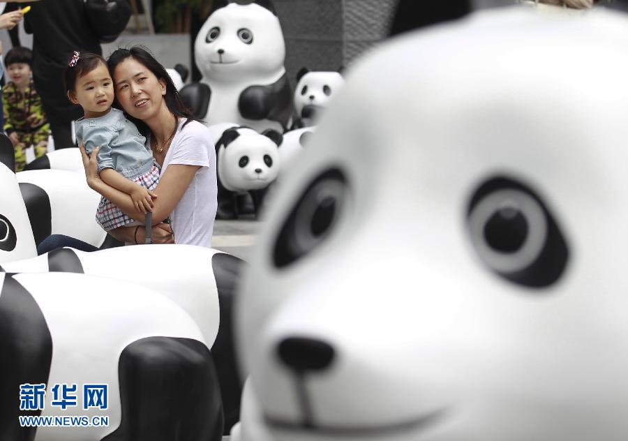 6月2日，一位家長帶著孩子在上海街頭和大熊貓模型合影。