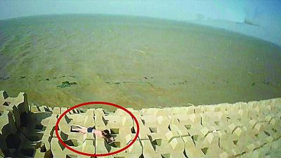 孫正龍游上岸，趴在海邊精疲力盡。