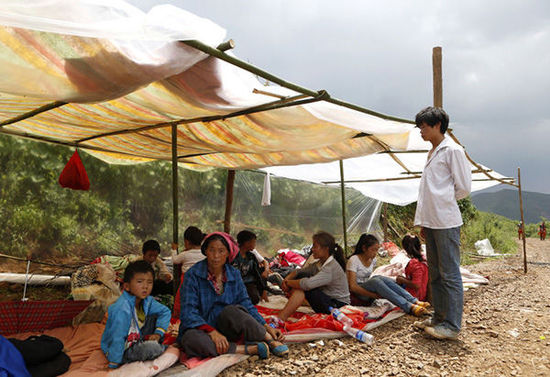 暴雨馬上來臨，村民們在簡易帳篷下躲雨。澎湃新聞 程藝輝 圖