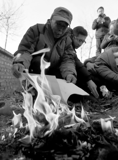 李三仁在兒子墳前焚燒再審無罪判決文書的復(fù)印件。新華社發(fā)