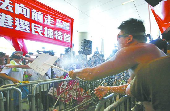 17日，在香港立法會外，一名反對政改的男子向支持派人群投擲標(biāo)牌。