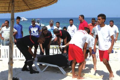6月26日，在突尼斯蘇塞，救生員和醫(yī)務(wù)人員在發(fā)生襲擊事件的海灘運(yùn)送一名死者的遺體。新華社發(fā)