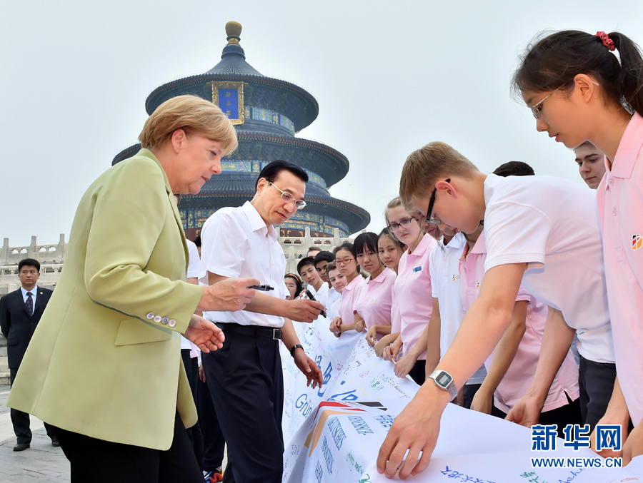 李克強(qiáng)同默克爾在紀(jì)念橫幅上簽名。