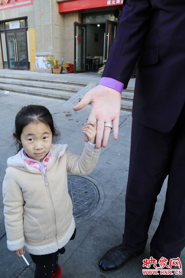巨人“張歡”牽著一名漂亮的小女孩，兩人的手大小對(duì)比非常明顯。