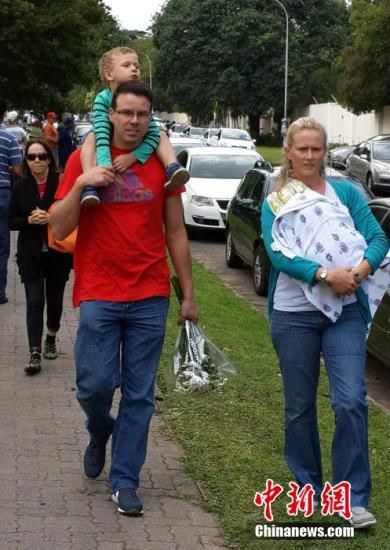 圖為一個白人家庭，由父母帶著孩子到曼德拉家門外悼念。中新社發(fā) 宋方燦 攝