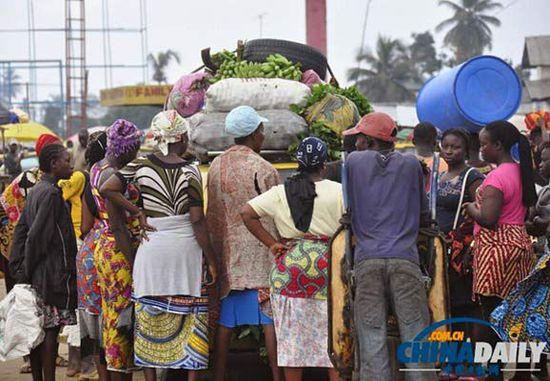 當(dāng)?shù)貢r(shí)間2014年8月14日，利比里亞蒙羅維亞，市場(chǎng)里的商人們圍著一輛汽車(chē)。