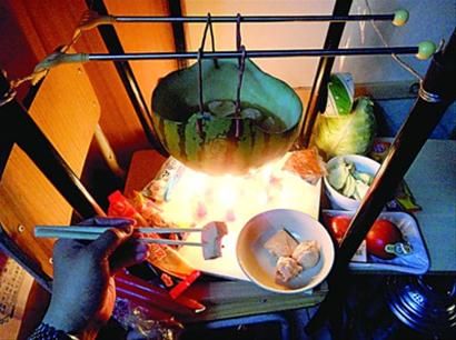 兩張椅子被面對面疊在一起，穿了兩根線的西瓜皮就懸空在椅腳中間，下面有蠟燭加熱，這就是西瓜火鍋。