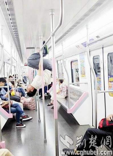 男子武漢地鐵里手握鋼管倒掛練“體操”(圖) 男子武漢地鐵里手握鋼管倒掛練“體操”(圖)