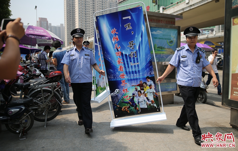 7月2日上午，鄭州市紫荊山地鐵站出入口，執(zhí)法人員抬著寫有勸導(dǎo)語的宣傳板，前往占道經(jīng)營攤位“圍觀執(zhí)法”